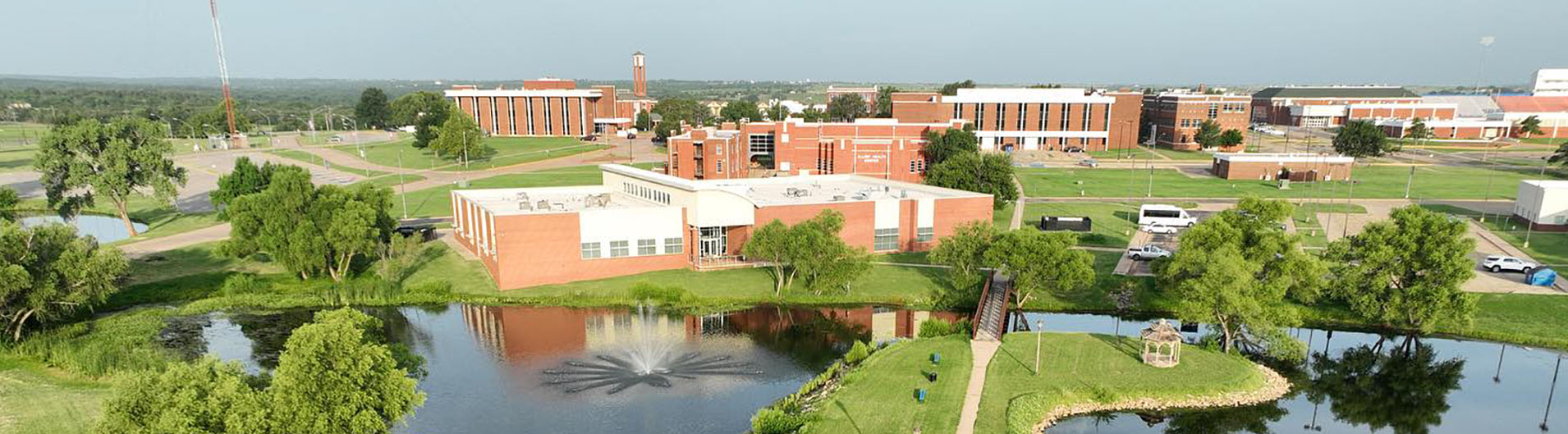 Photo of campus buildings in background and ponds and bridge in forefront