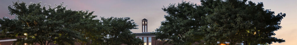 Photo of Langston main campus with clock tower and trees in an evening sky