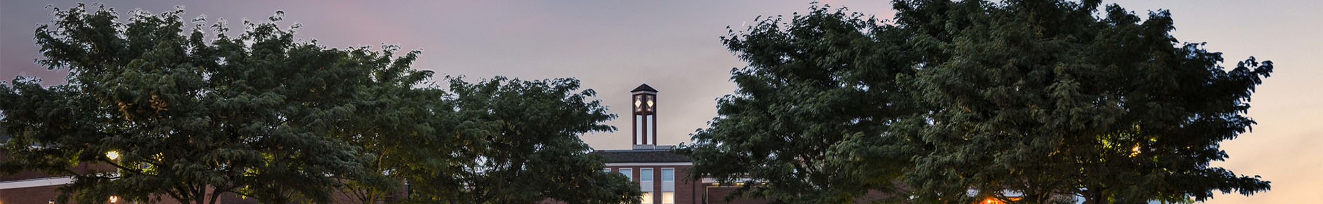 Photo of Langston main campus with clock tower and trees in an evening sky