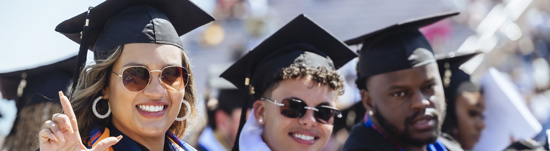Image of students in regalia smiling at commencement