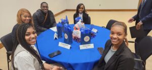 LU students sit around a table smiling during the "Careers in Sports Event with OKC Thunder."