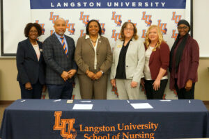 representatives of Langston University and Redlands Community College pose in front of an LU backdrop