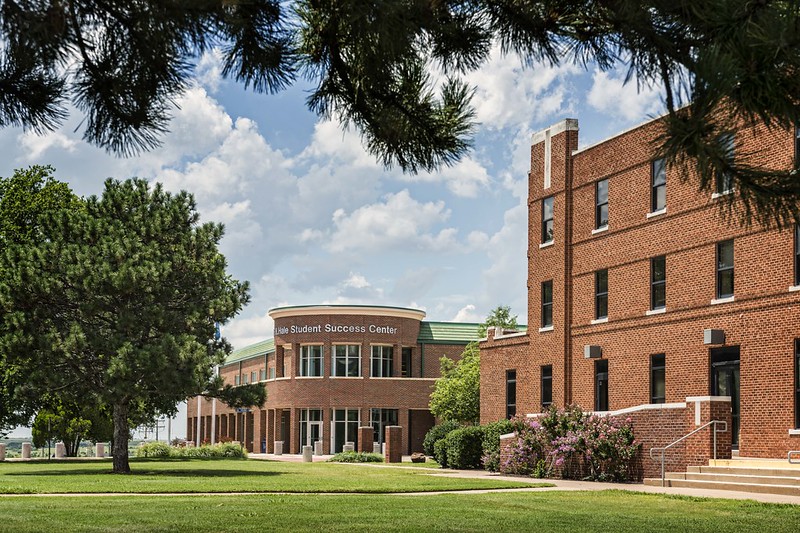 Photo of Student Success Center in foreground on campus - looking from under a pine tree.