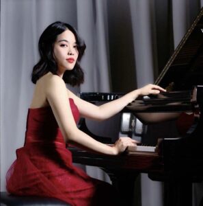 Meichen Hou Hughbanks plays the piano in a red dress