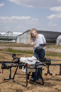 Josie Throckmorton looking at a large drone in a field.