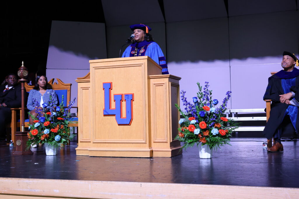 Dr. Jackson speaks at a podium in full academic regalia