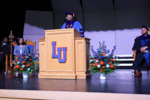 Dr. Jackson speaks at a podium in full academic regalia