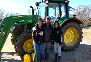 Cleaon Bradford poses with his children in front of a tractor