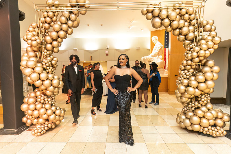 Photo of a guest between the golden balloons disiplay during the Gala