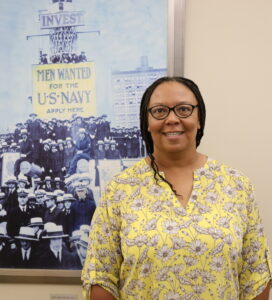 Sharon Caldwell poses in front of a U.S. Navy recruitment poster