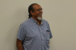 Dr. Herron smiles while standing at the front of a classroom