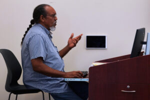 Dr. Herron sits at a desk in front of a computer