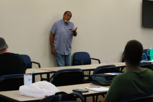 Herron stands at the front of a classroom teaching.