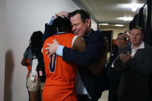 Former head men's basketball coach Chris Wright hugs #0 Orlando Thomas after a game.