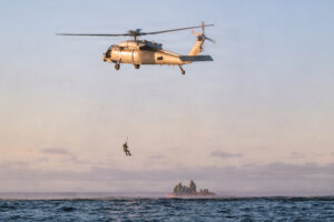 helicopter with a Navy Diver hovers above the Orion capsule in the Pacific Ocean