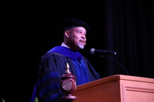 Vice President for Academic Affairs Alonzo Peterson dressed in academic regalia addressing the crowd during Opening Convocation