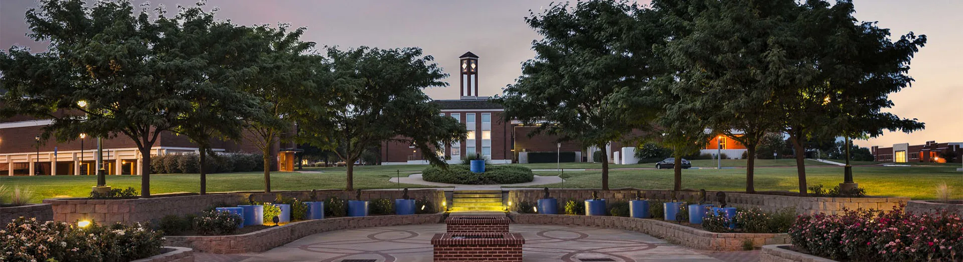 Photo of clock tower in background and mall area in foreground as evening approaches