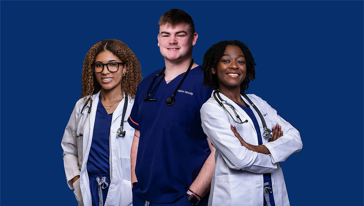 Three nursing students on blue background in hospital scrubs and white hospital coats